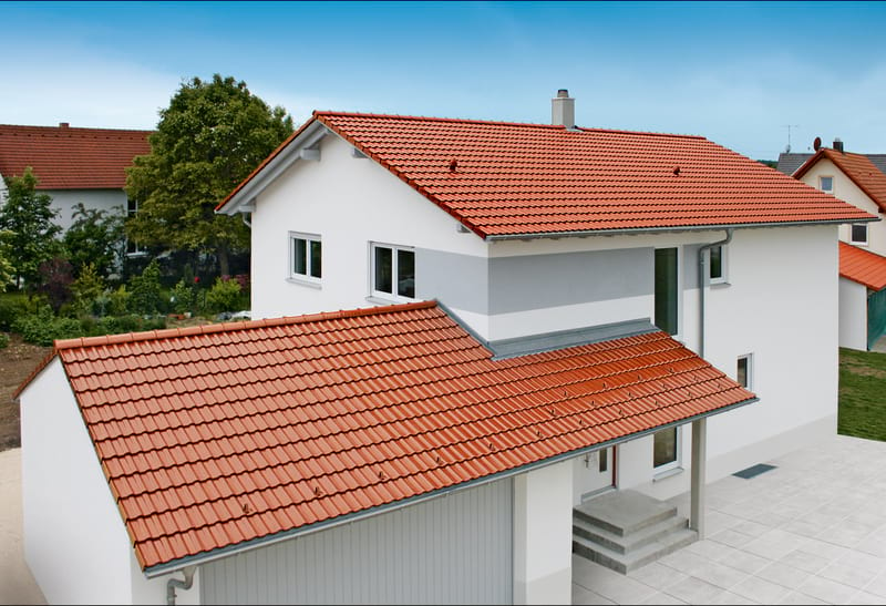 A white home with red metal shingle specialty roofing.