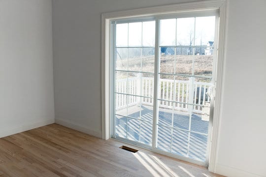 Sliding patio doors on the interior of a home leading to a white deck.