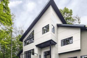 A modern home with white siding and black trim around the roof and windows.