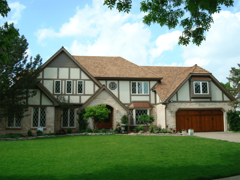 A 2 story home with ivory siding, brown vertical accent siding, and brick along the first story.