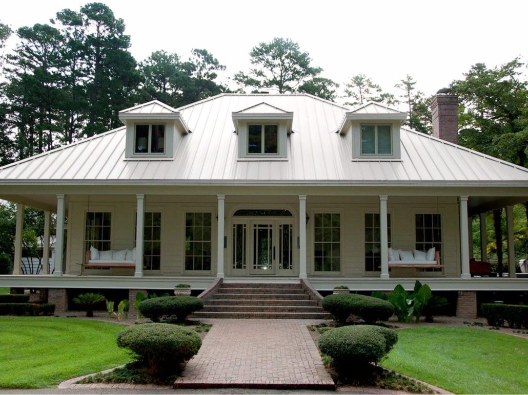 A 2 story home with white siding and a white standing seam roof.