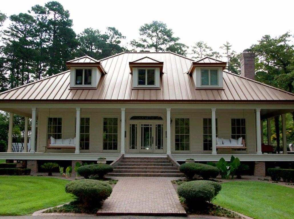 A 2 story home with white siding and a bronze standing seam roof.