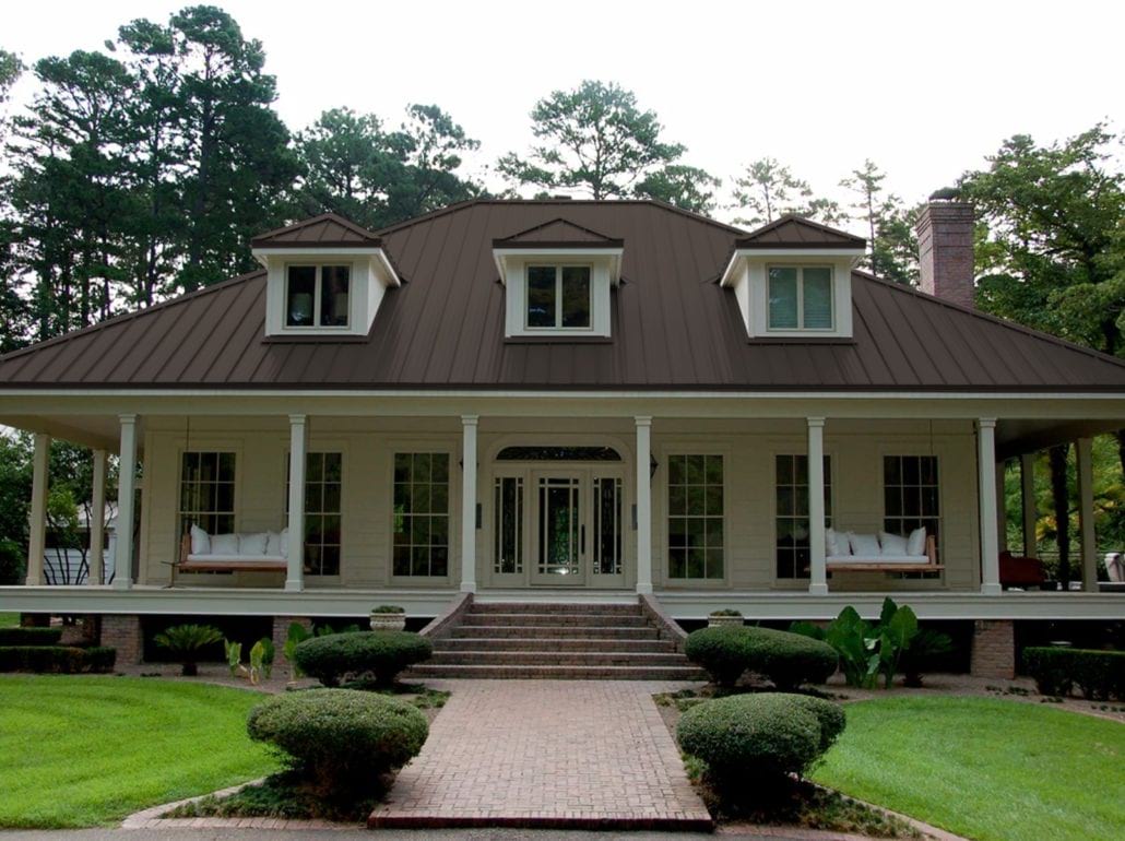 A 2 story home with white siding and a maroon standing seam roof.