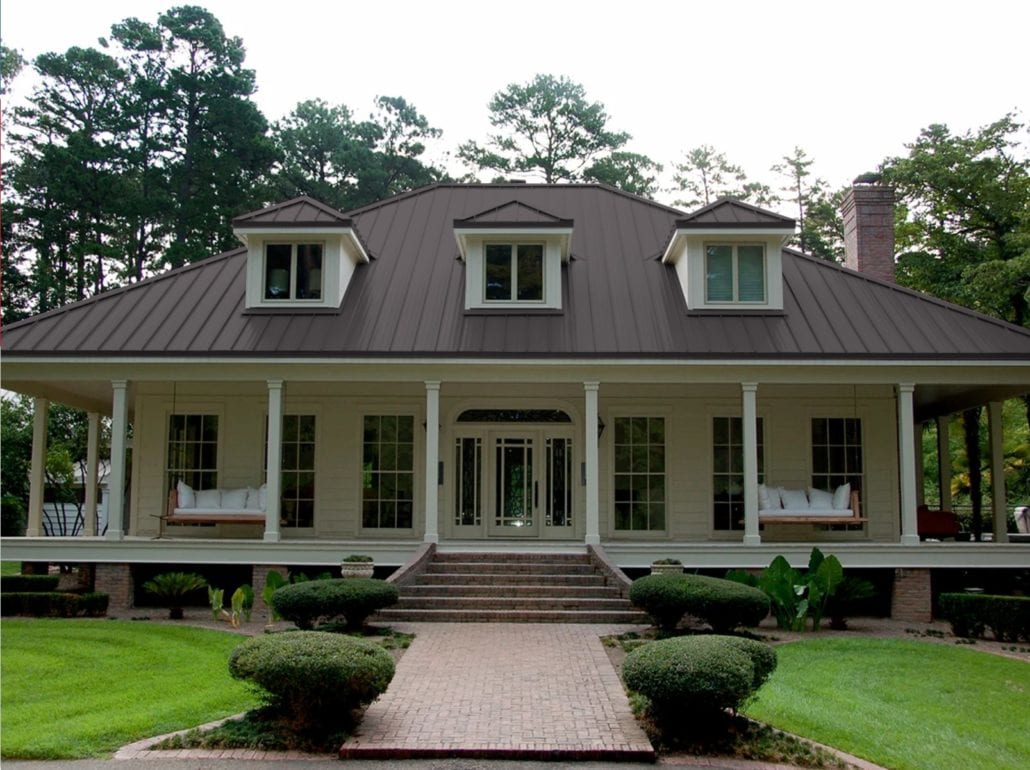 A 2 story home with white siding and a gray standing seam roof.