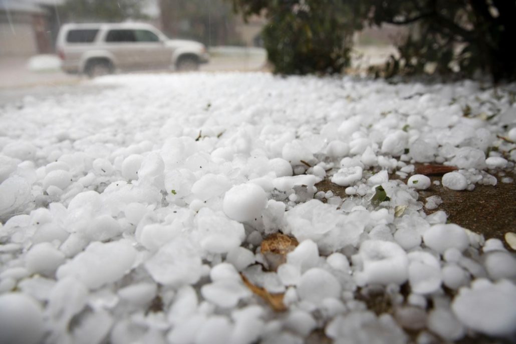 Hail pieces accumulating on the ground during a storm.