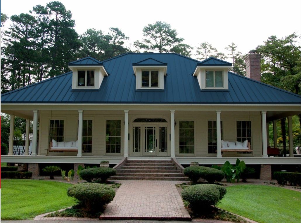 A 2 story home with white siding and blue standing seam roof.