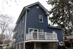 A Dover, NH home with blue vinyl siding and white trim and railings.