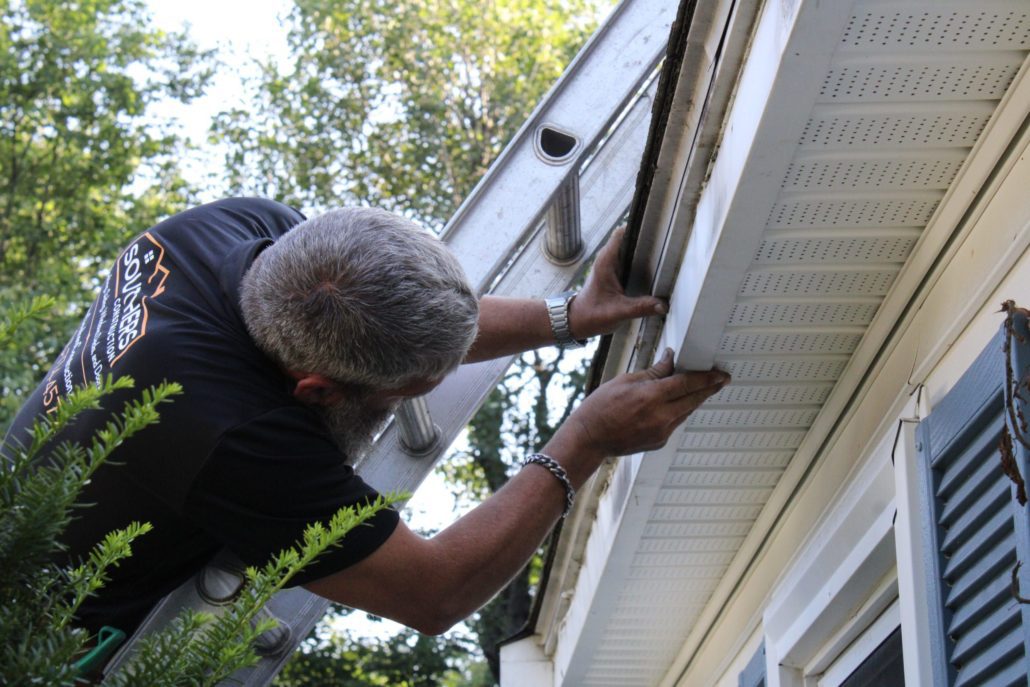 Construction Worker Applying Gutters To a House.