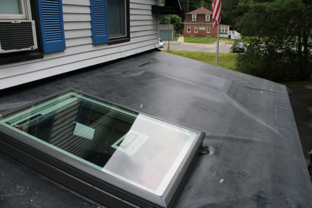 A new skylight on a home's flat black rubber roof.