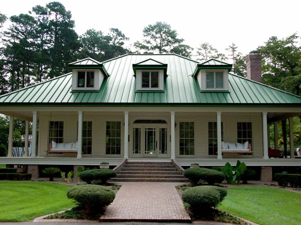 A 2 story home with white siding and a green standing seam roof.
