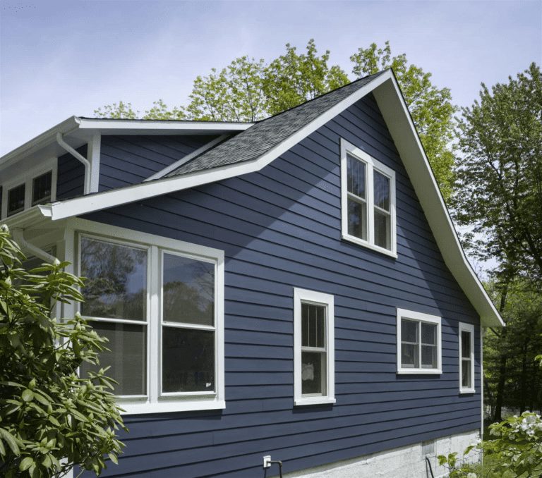 The side of a home with dark blue clapboard siding and white trim and windows.