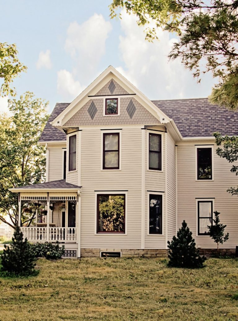 A 2 story home with white siding and black trim around the windows.