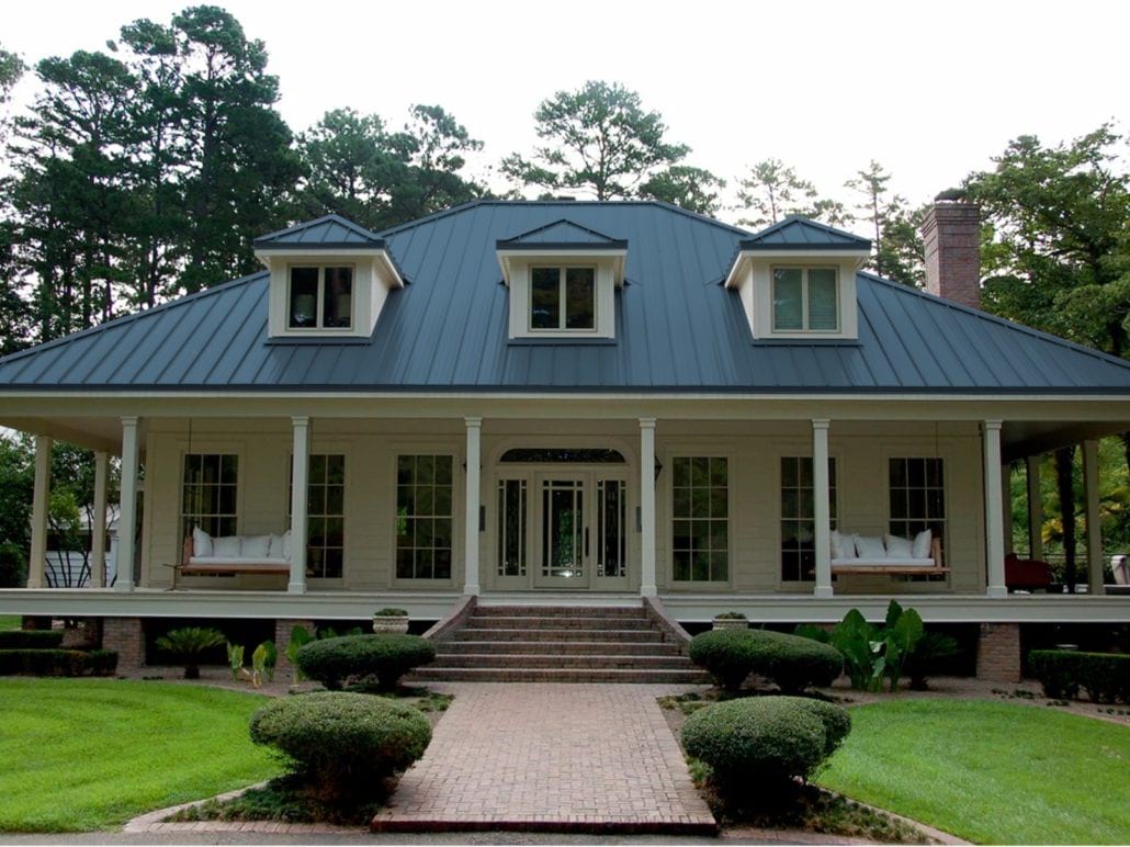 A 2 story home with white siding and a navy blue standing seam roof.