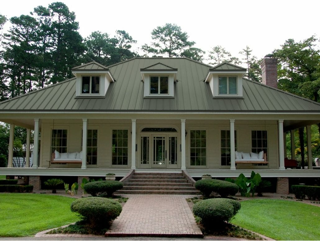 A 2 story home with white siding and an olive green standing seam roof.