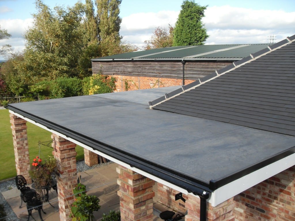 A brick home with a flat rubber roof over its patio.