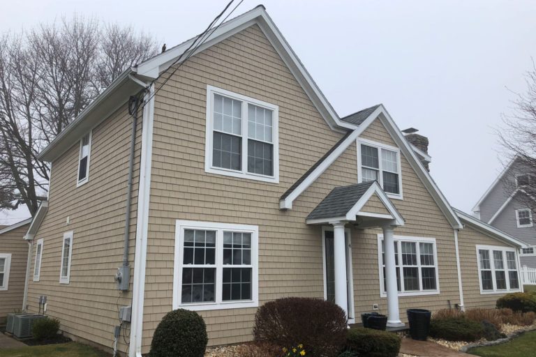 A 2 story home with tan Tando Cape Cod Perfections shake siding and white trim.