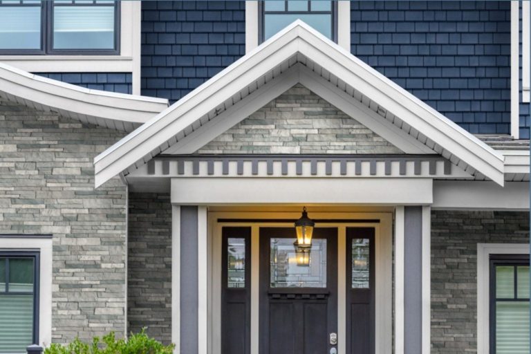 The entry way of a home with a dark brown door surrounded by gray TandoStone and blue TandoShake siding.