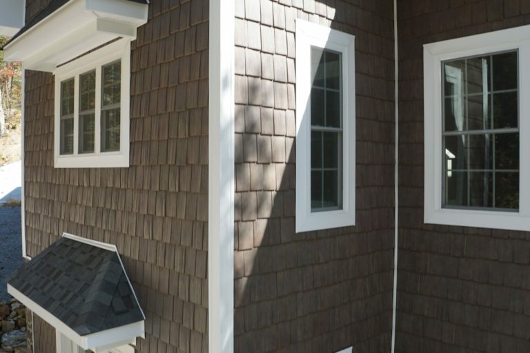 Brown Tando Shake siding with white trim and windows.