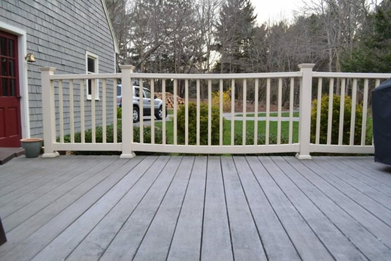 A wood deck with warped ivory railings.