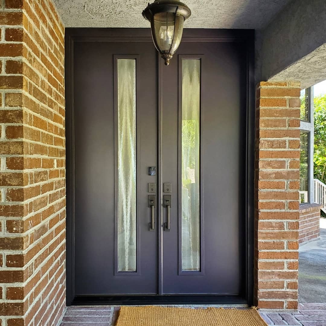 Dark brown double fiberglass entry doors on the exterior of a brick home.