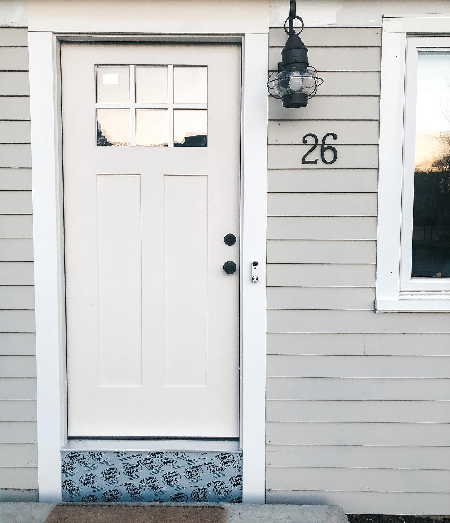 An off-white fiberglass entry door with white trim on a home with off-white siding.