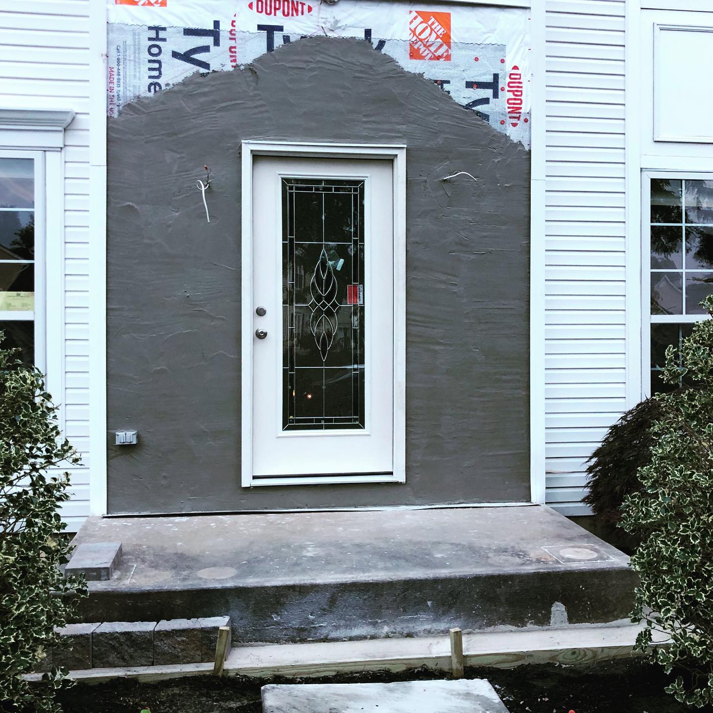 A white fiberglass entry door with decorative glass on a home with an unfinished entry way.