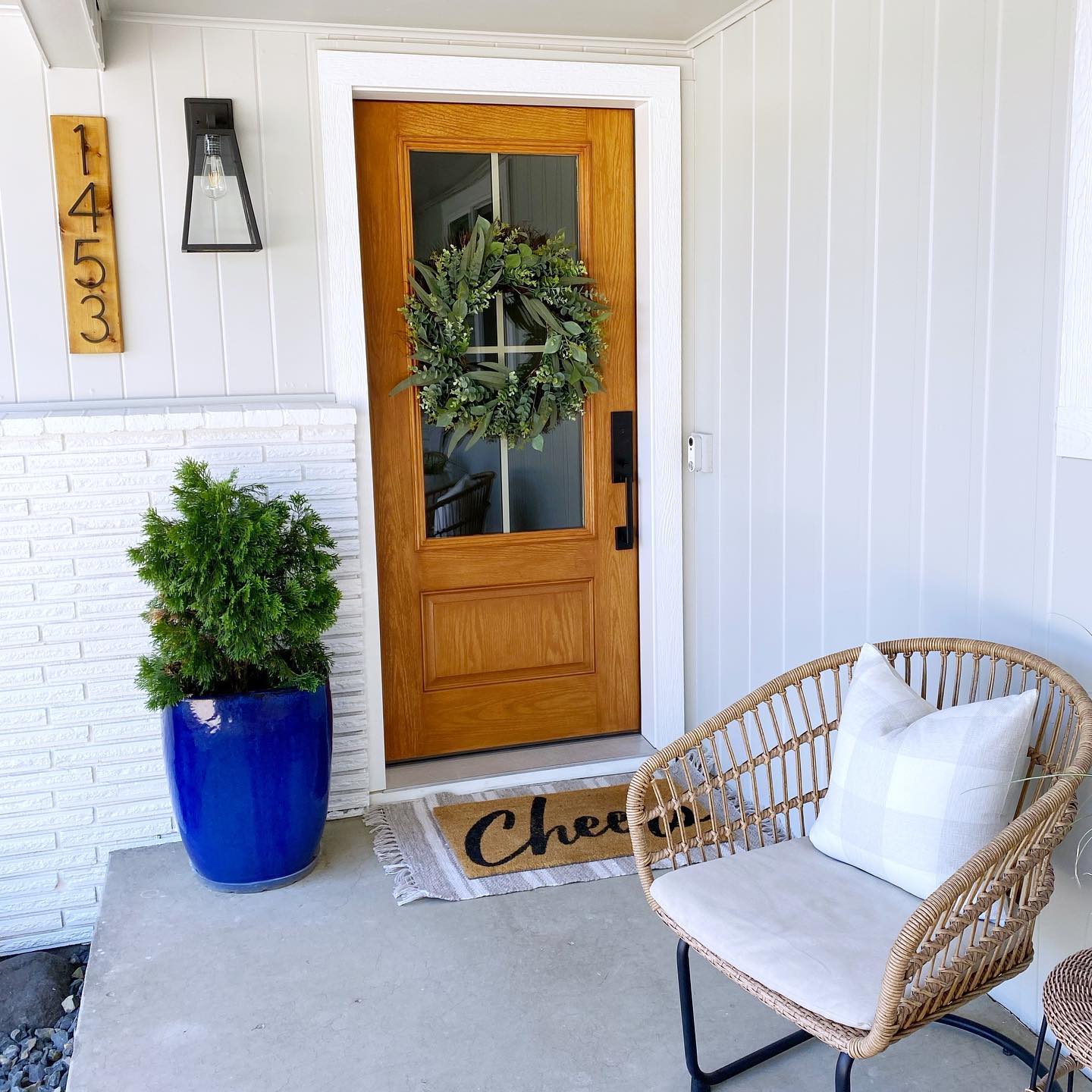 A wood entry door with 4 glass panes on a white home with a cement porch.