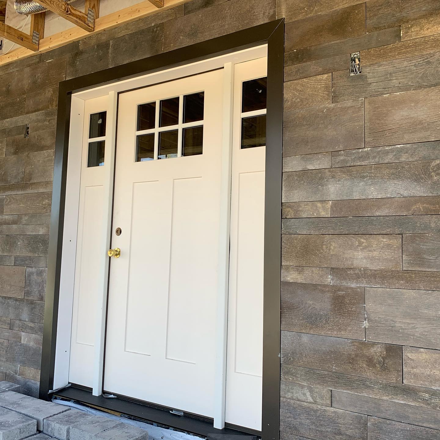 A white fiberglass entry door with black trim on the exterior of a home.