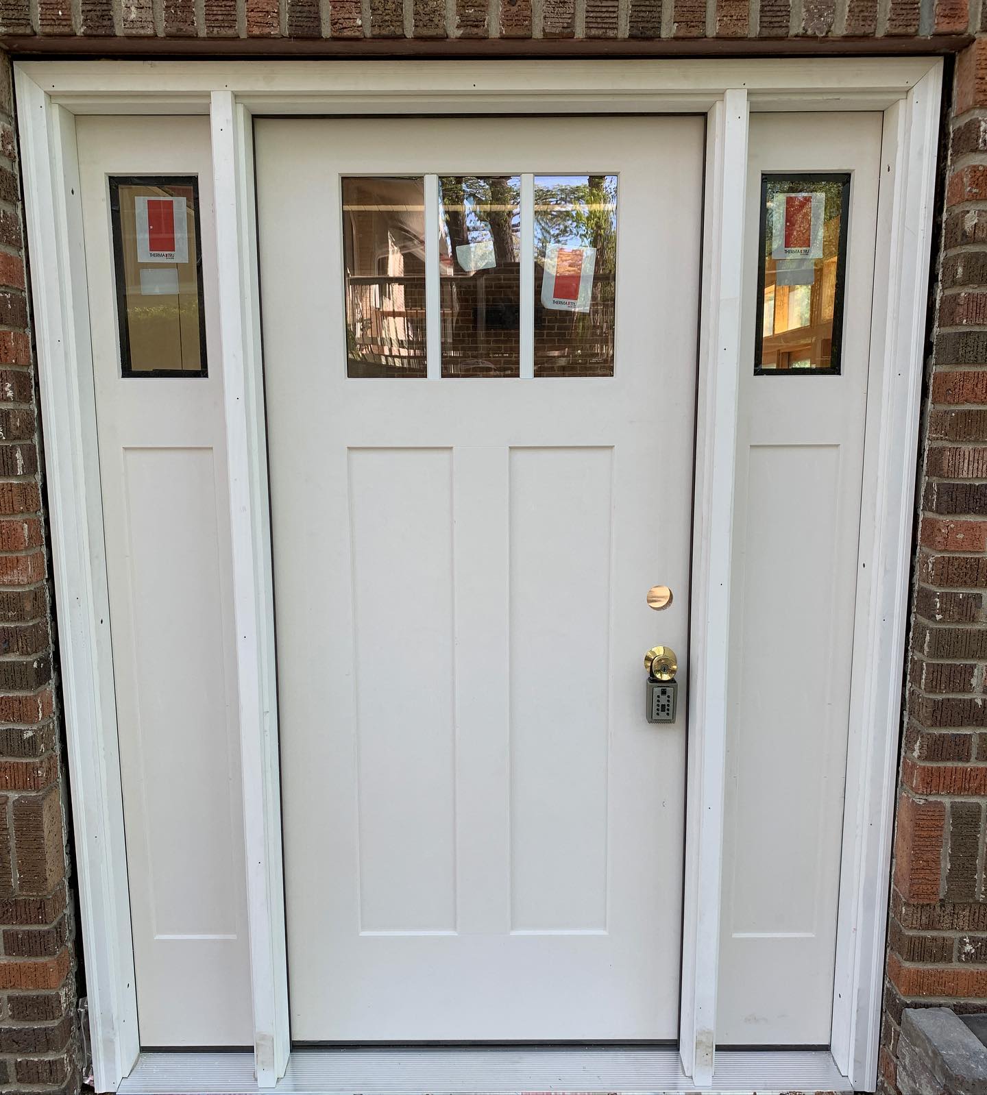 A white fiberglass entry door on a brick home.