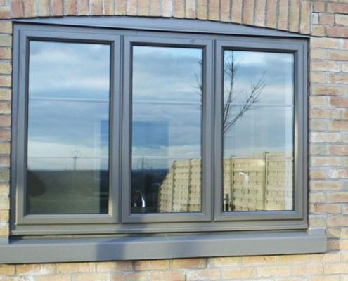 A bay window with black trim on a brick home.