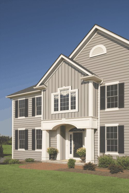 A home with tan Royal clapboard and board and batten siding. There is white trim and black shutters around the windows.