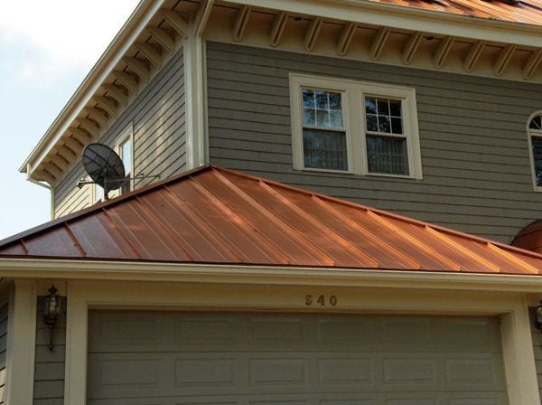 A beige home with copper standing seam roofing and cream trim.