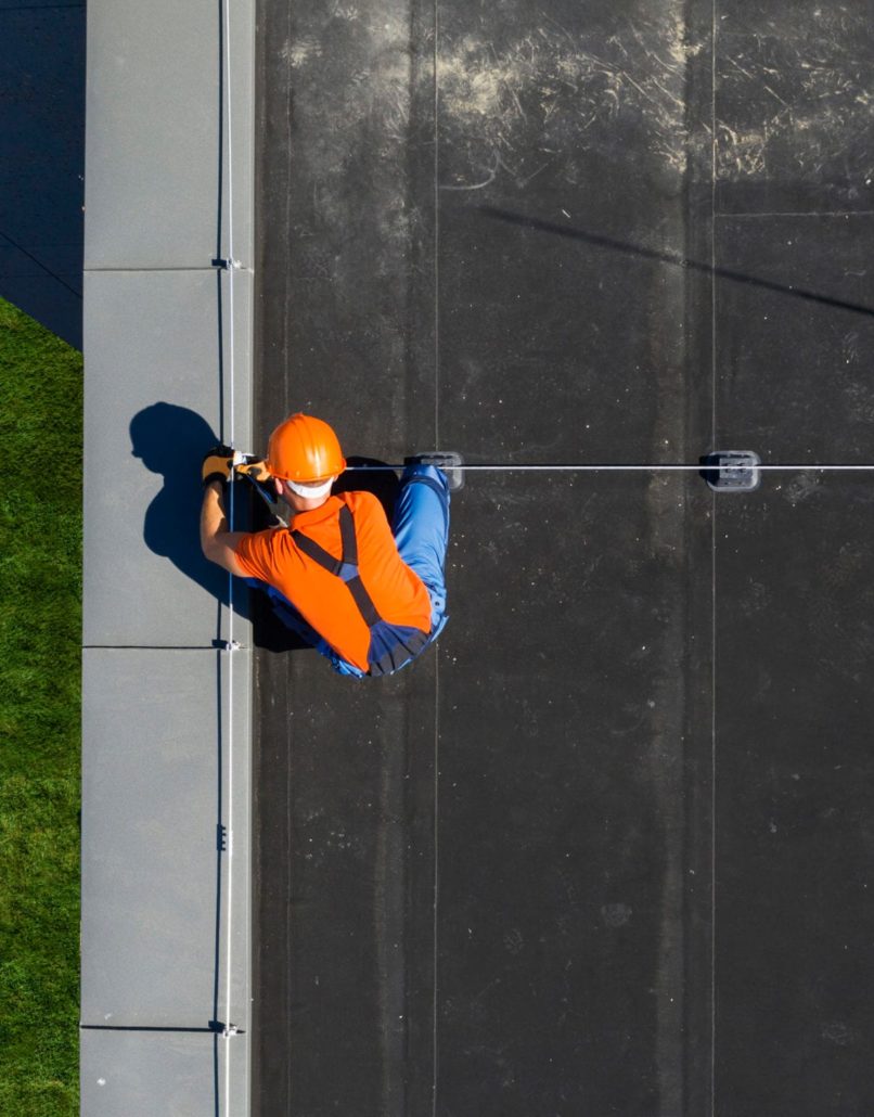 A construction worker putting a new rubber membrane on a residential roof.