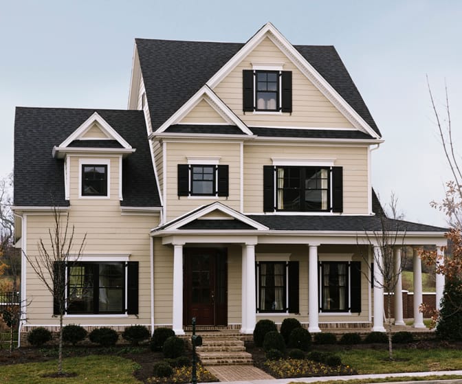 A large 3 story home with cream HardiePlank siding, white trim, and black shutters.