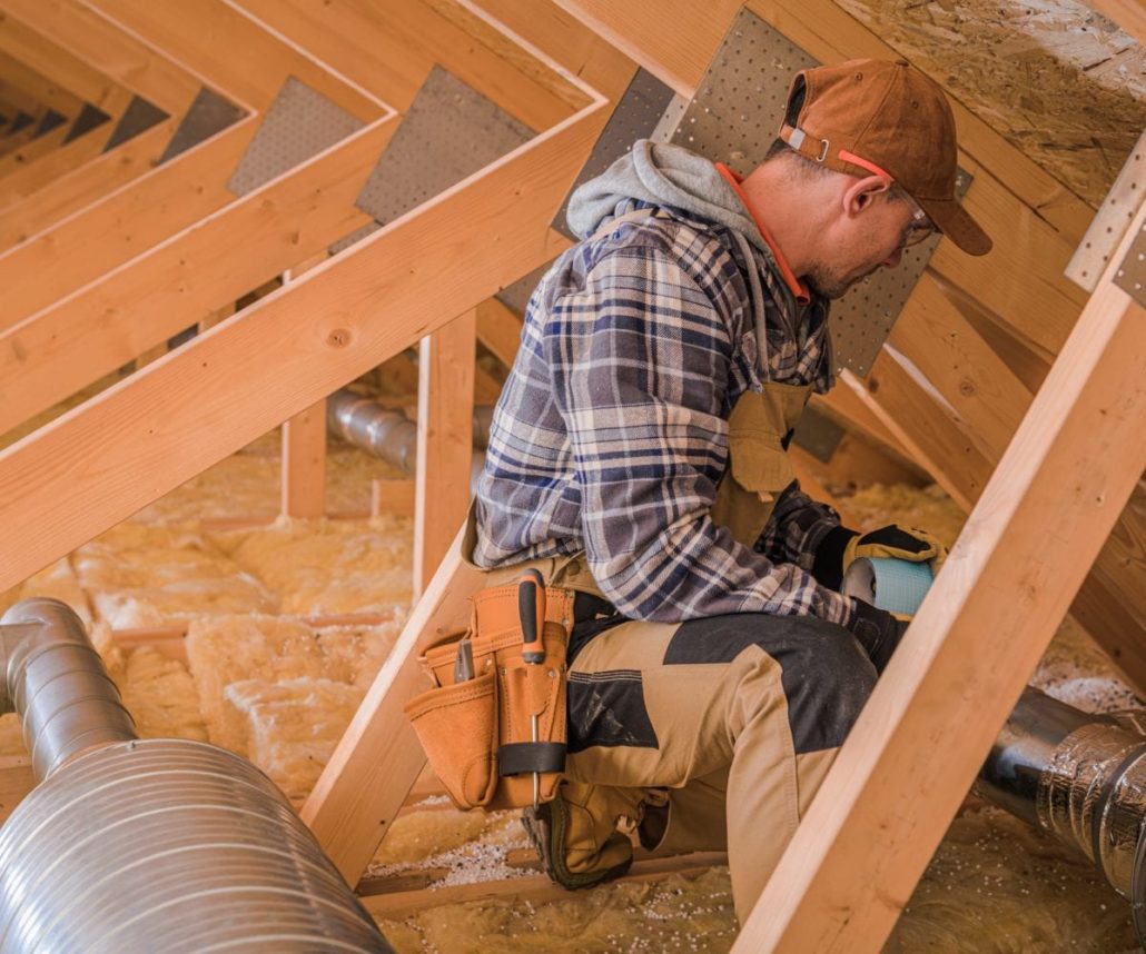 A construction working working in a home's attic.
