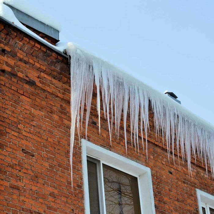A brick home with ice dams and icicles hanging from the gutters.