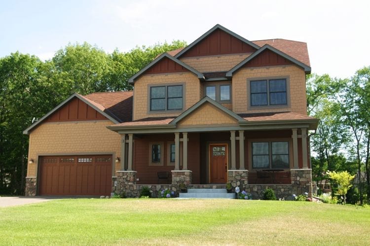 A large 2 story home with tan shake and mahogany board and batten JamesHardie siding.