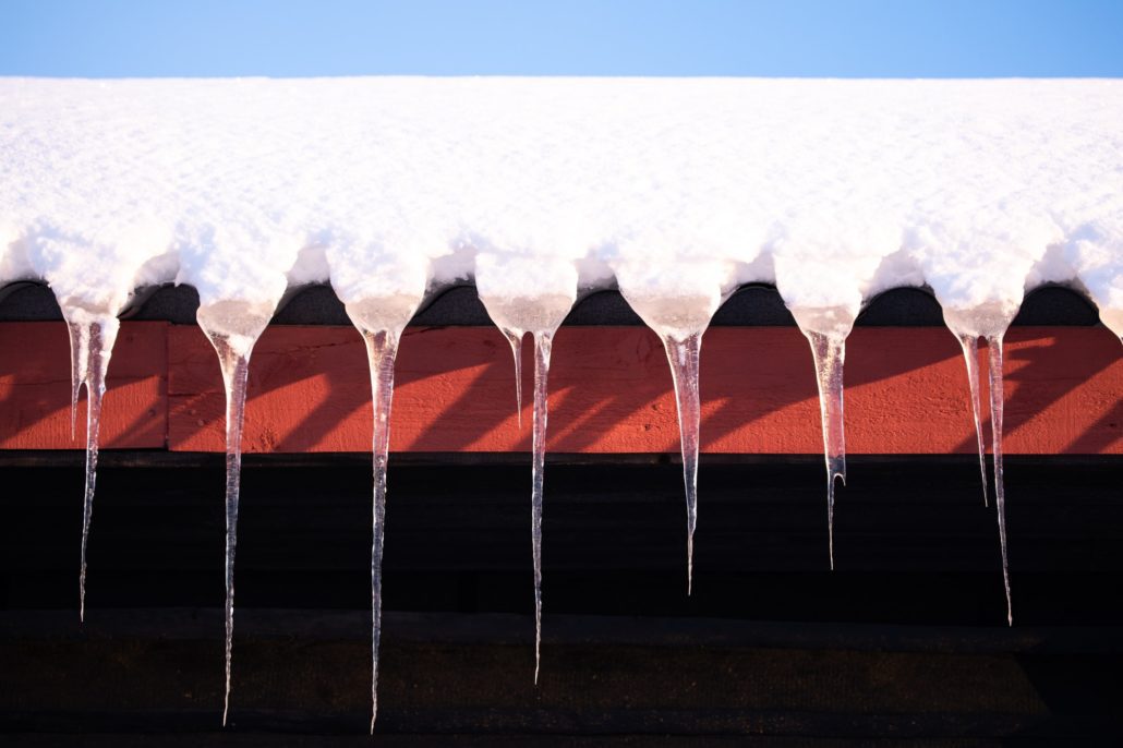 Icicles hanging from a snow covered roof.