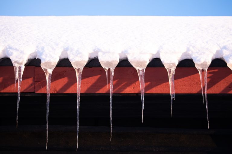 Icicles hanging from a snow covered roof.