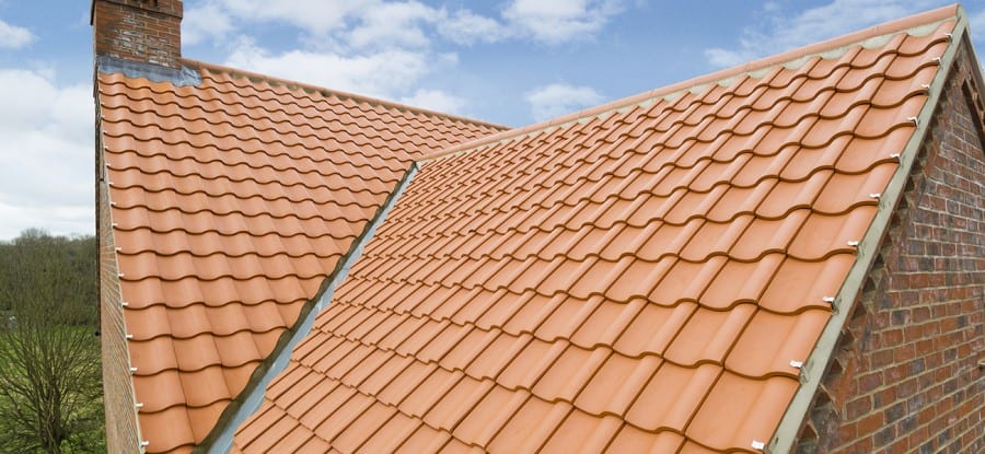 Orange metal clay tiles on the roof of a brick home.