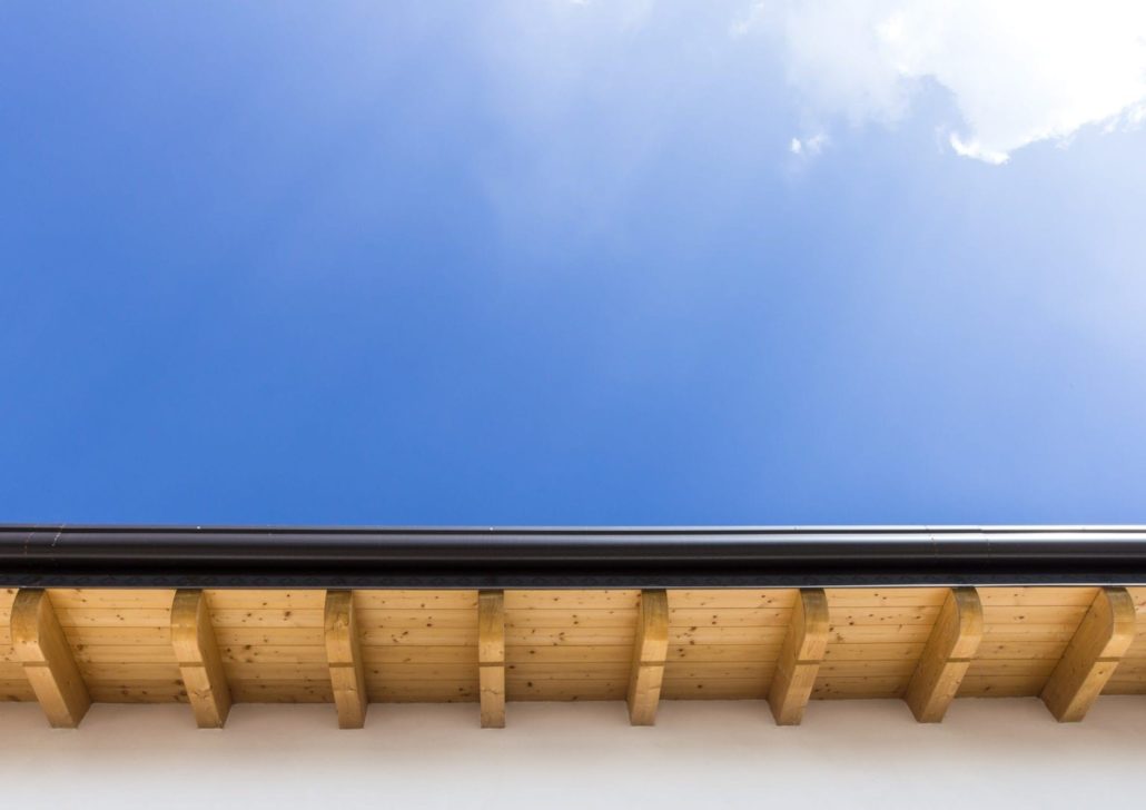 An underside view of a home’s new roof and black seamless gutters.
