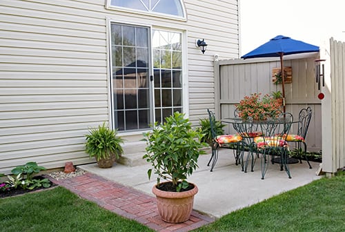 A backyard patio with sliding patio doors leading into the home.