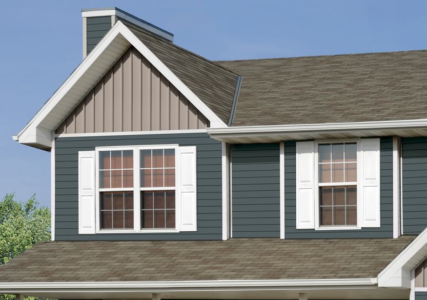 A home with dark blue Premium Pointe vinyl and tan board & batten siding. There are white shutters and trim around the windows.