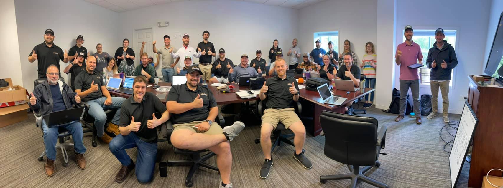 A group of employees giving thumbs up for a group picture in an office in Dover, NH.