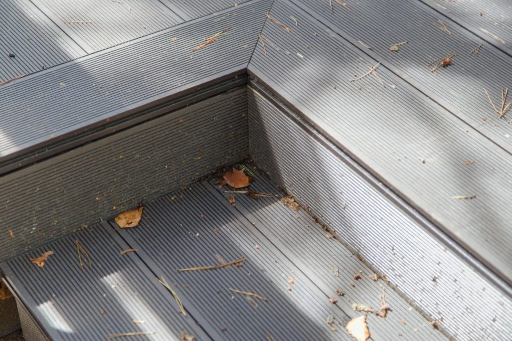 A gray composite deck covered in leaves and dirt.