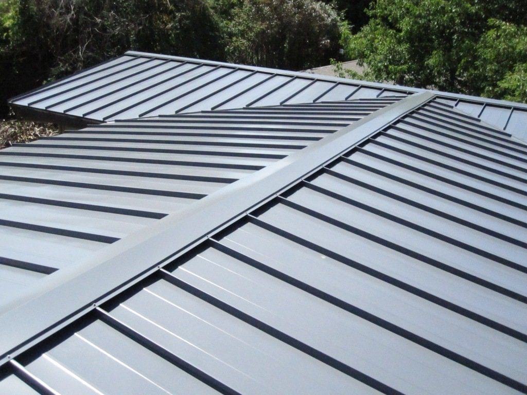 The peak of a roof with black standing seam metal roofing.