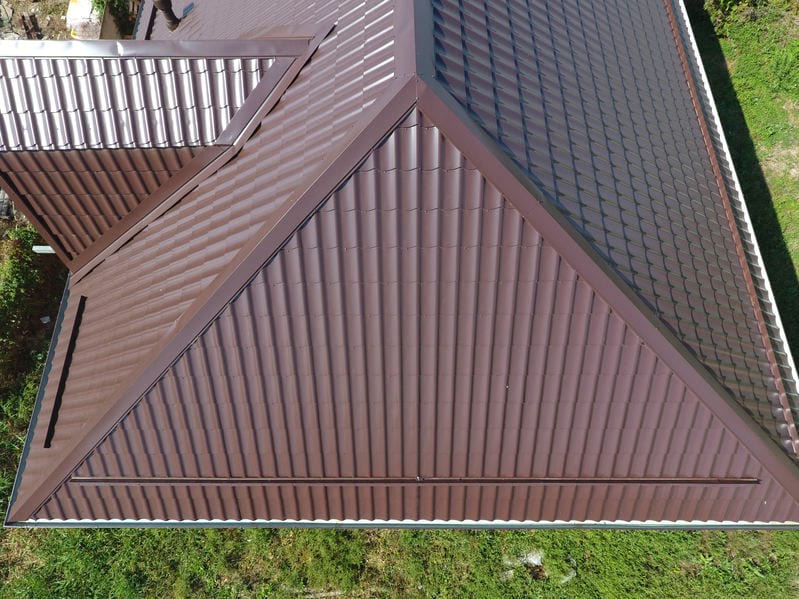 The top of a home's maroon corrugated metal roof.