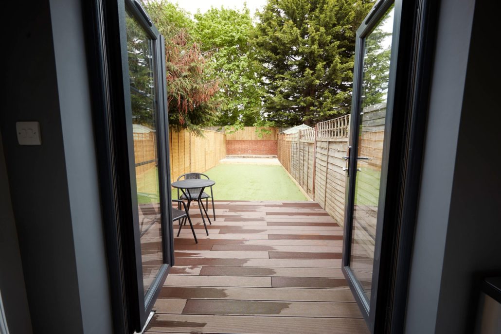 Black double hinged patio doors opening to a backyard patio area.