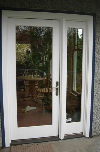 A glass hinged patio door with white trim.