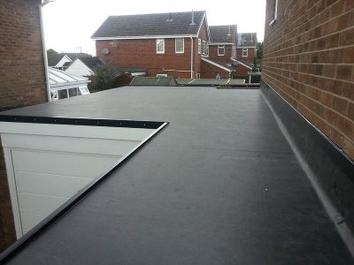 A flat black EPDM roof in a residential neighborhood.